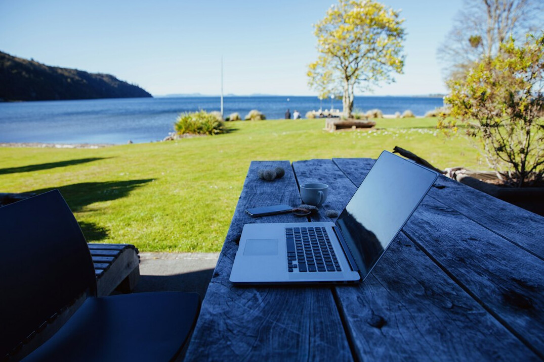 Laptop and notebook on a wooden desk with a cup of coffee